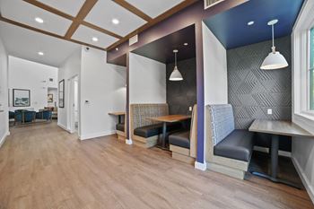 A seating area with tables and chairs in the center of a room with a blue accent wall